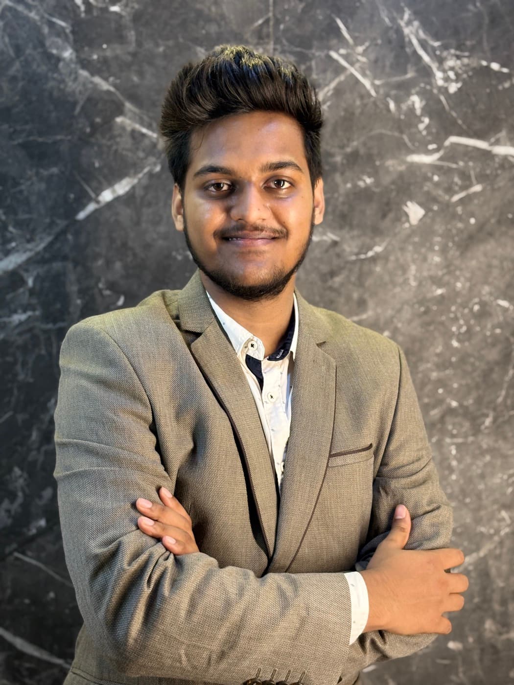 Aniket Kumar smiling in front of a dark marble wall