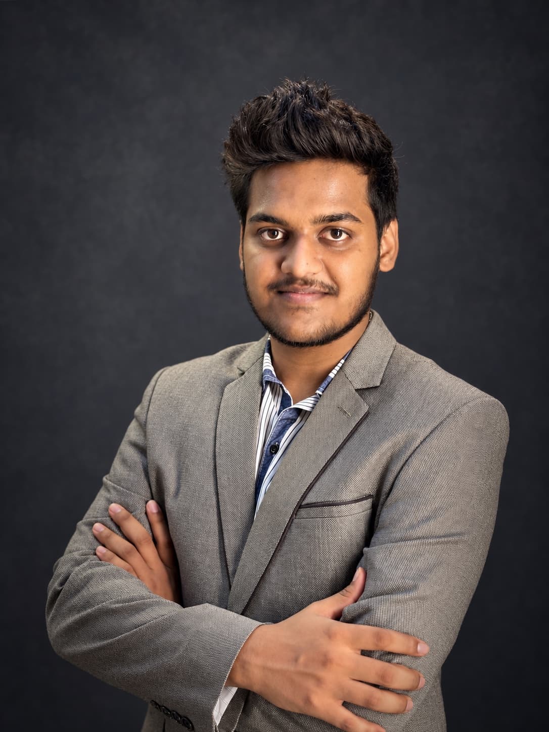 Aniket Kumar in a grey blazer, arms crossed, smiling slightly